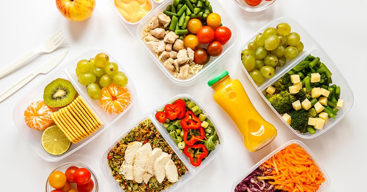 Prepped fruits, vegetables, and lean proteins in containers on white kitchen countertop.