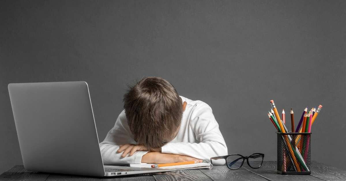 young child falling asleep on school desk 