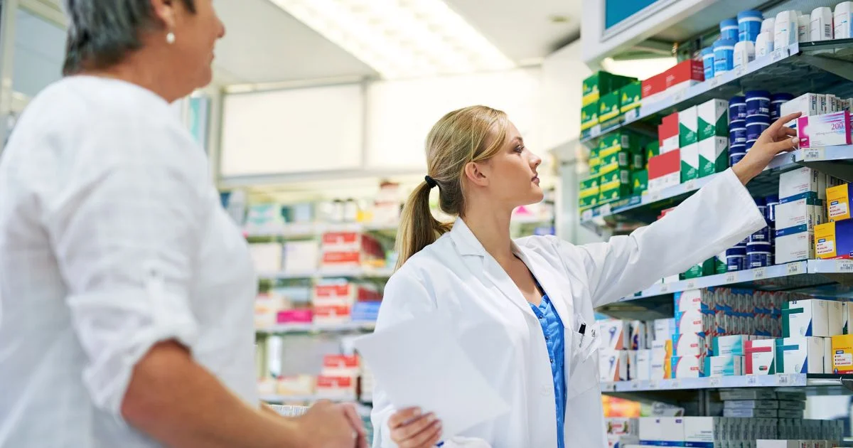Pharmacist selecting medication from pharmacy shelf